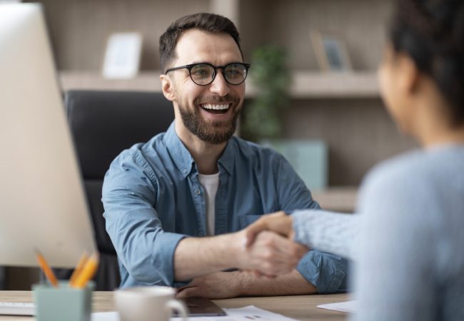 Partnership. Smiling Male Entrepreneur Giving Hand For Handshake To Female In Office Partnership Concept. Smiling Young Male Entrepreneur Giving Hand For Handshake To Female In Office, Friendly Businessman Greeting Young Woman And Offering Cooperation, Selective Focus